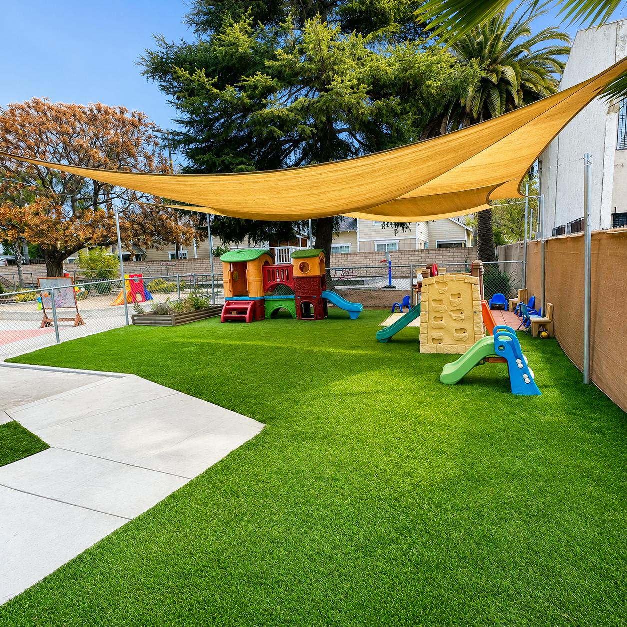 Childrens playground with plastic slides and playhouses under a shade sail