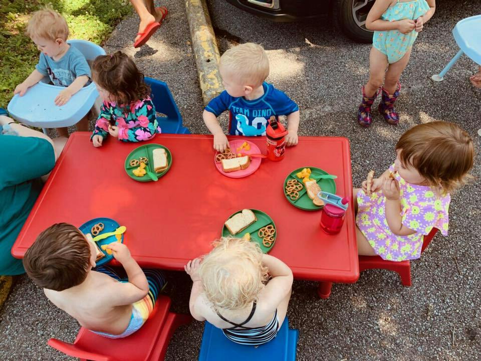 Children eating at a red table outdoors