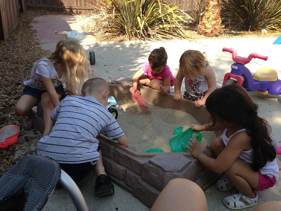 Children playing in a sandbox with toys