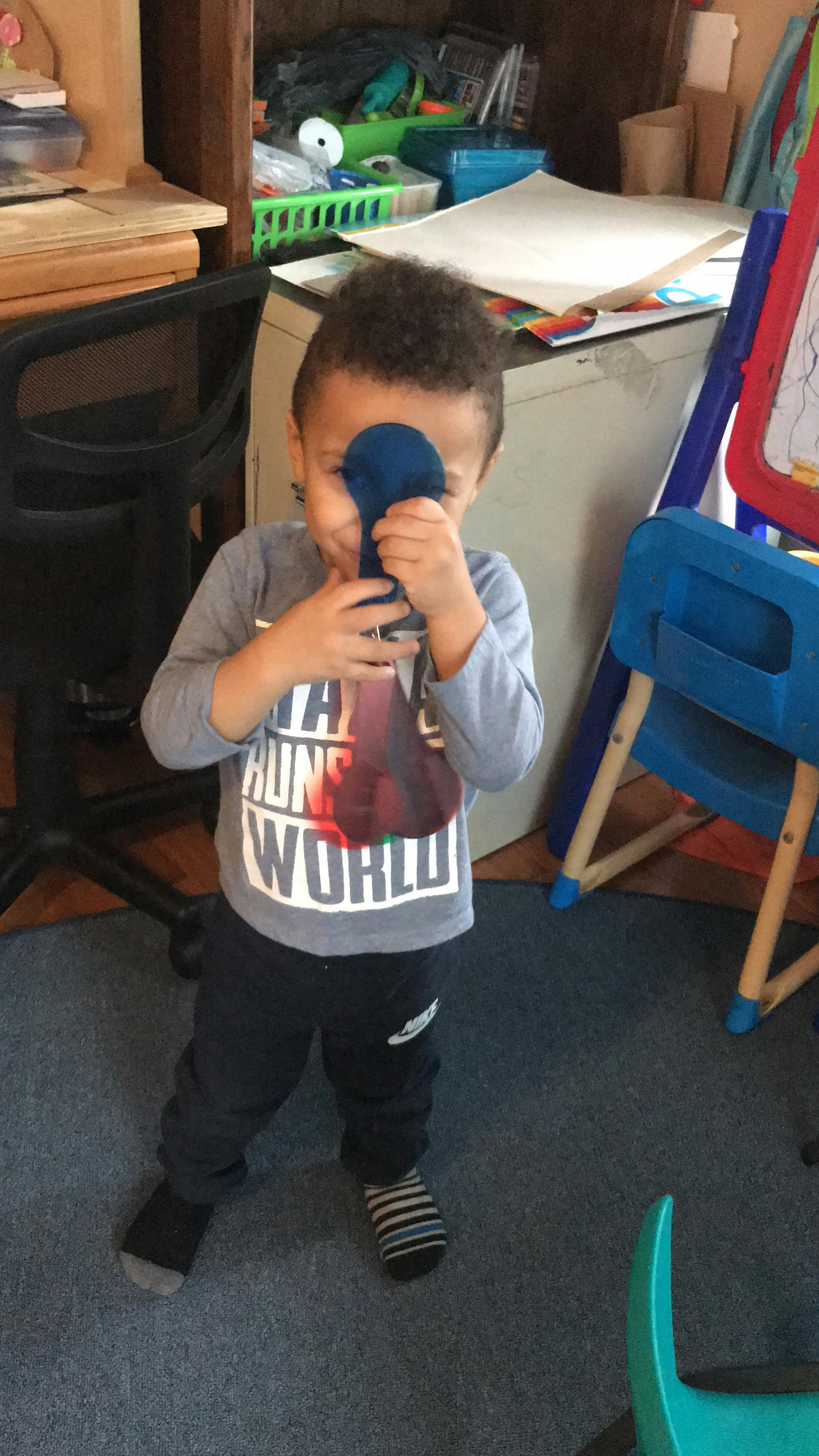 Child holding a blue object to their face
