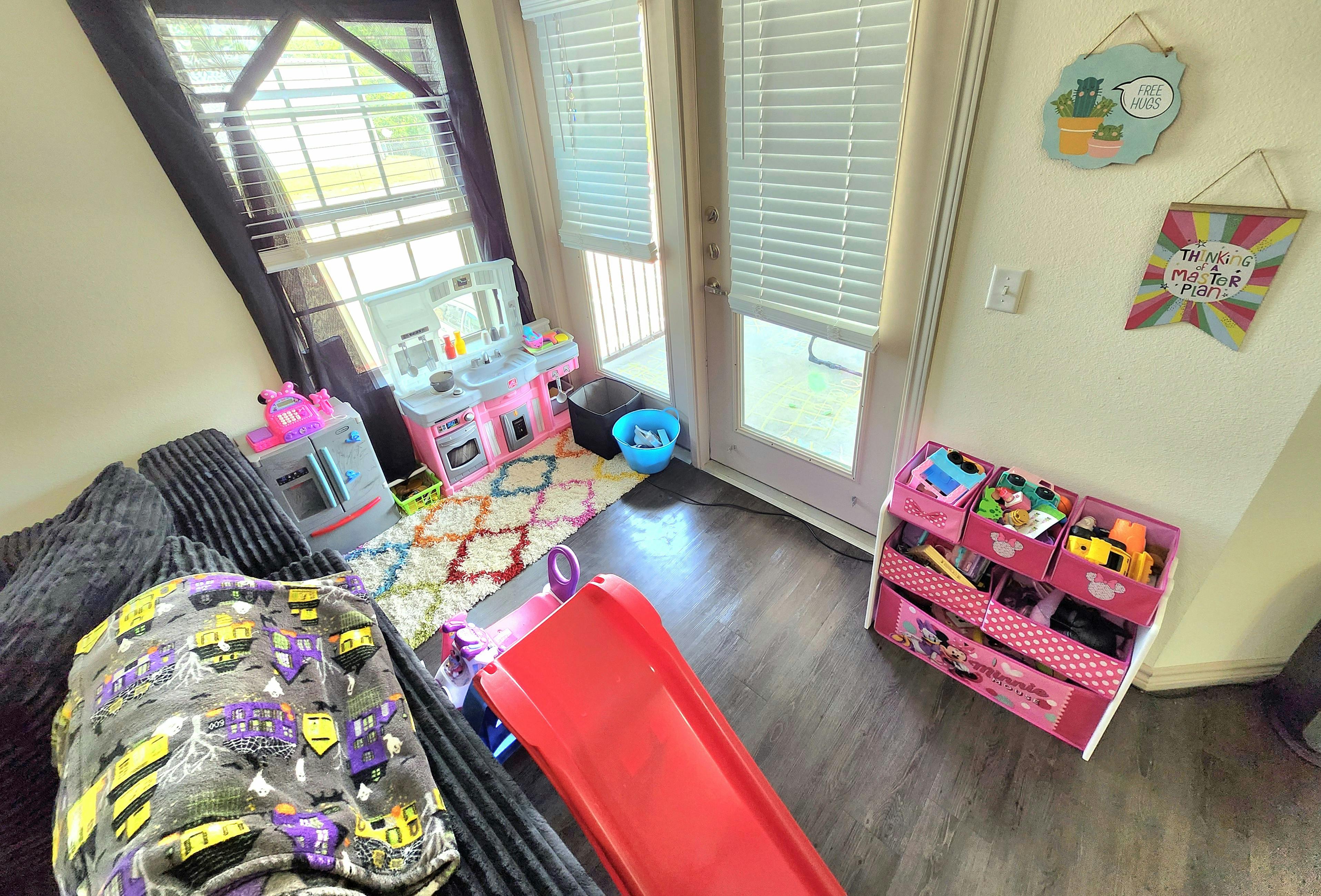Play area with toy kitchen, slide, and storage bins