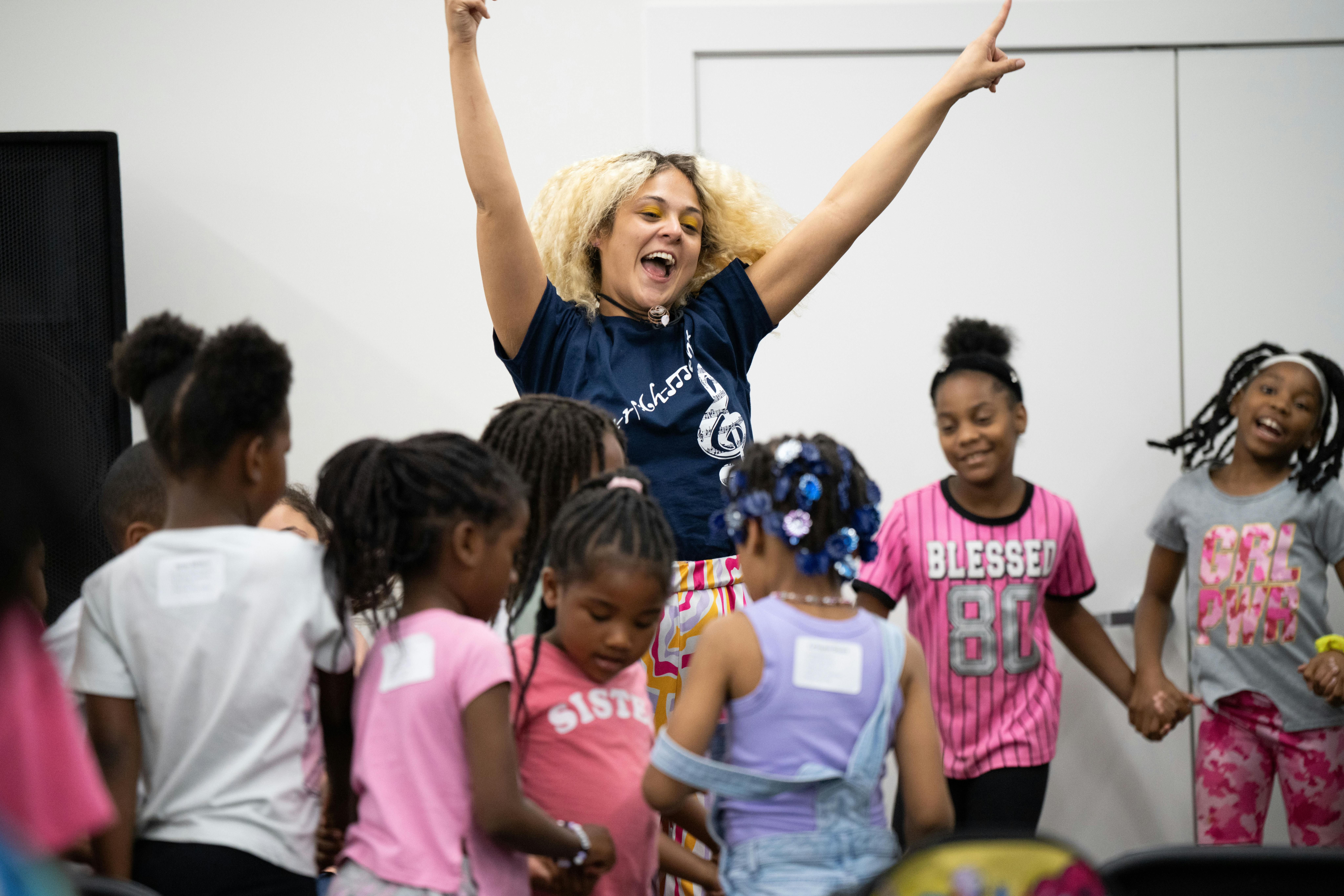 Person with arms raised surrounded by children