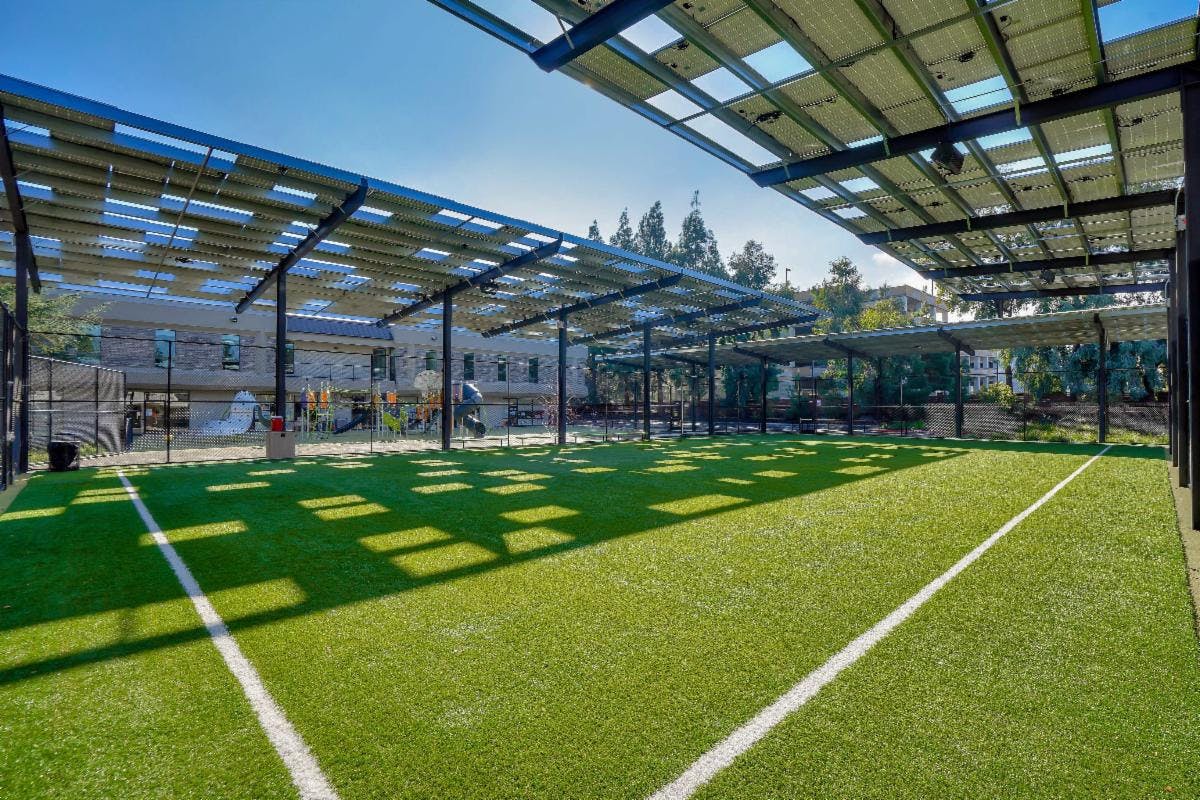 Outdoor sports court with artificial turf and solar panel canopy