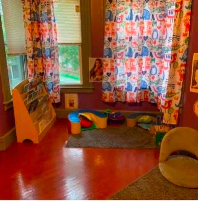 Children's room with a bookshelf, colorful curtains, and play items