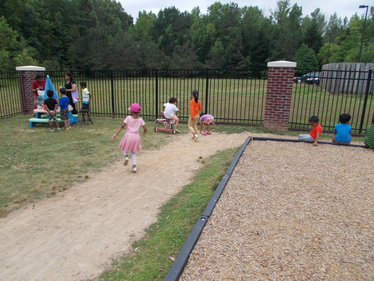 Children playing on a playground with a sandpit and grassy area