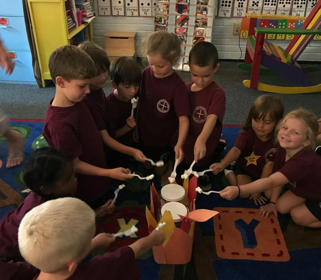 Group of children playing with spoons and containers on a colorful mat