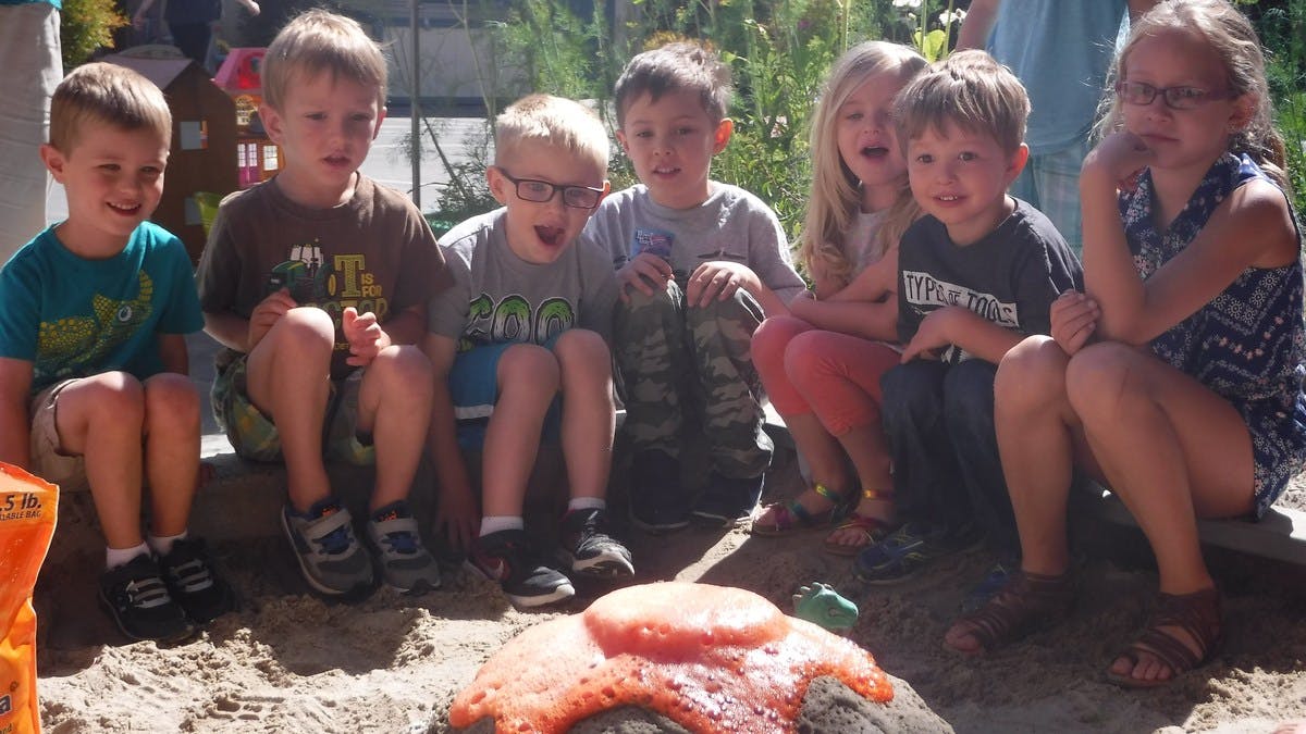 Group of children watching a science experiment with a volcano model