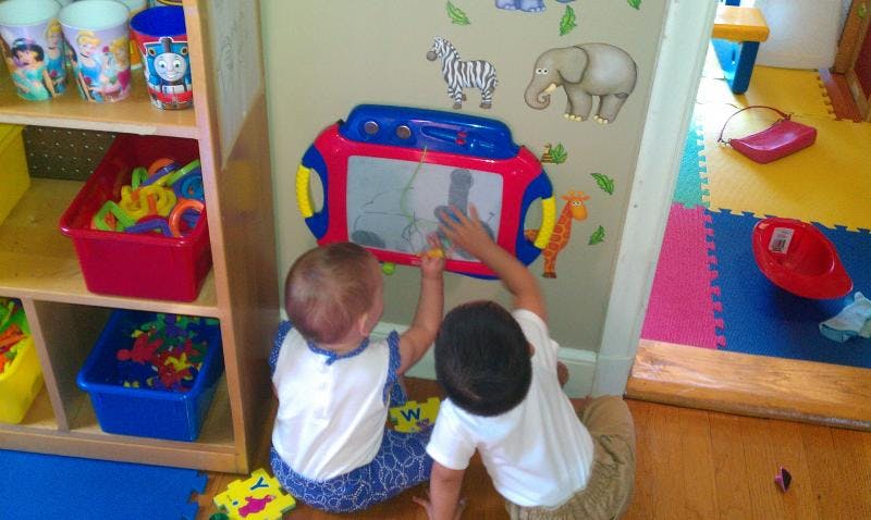 Two children playing with a magnetic drawing board in a classroom