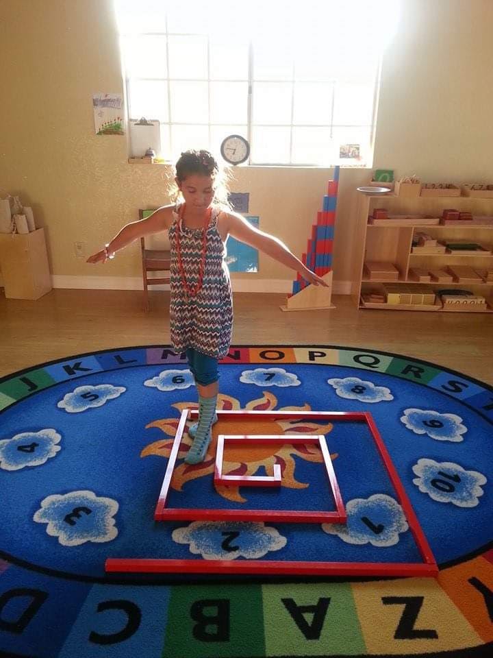 Child balancing on one foot on a rug with letters and numbers