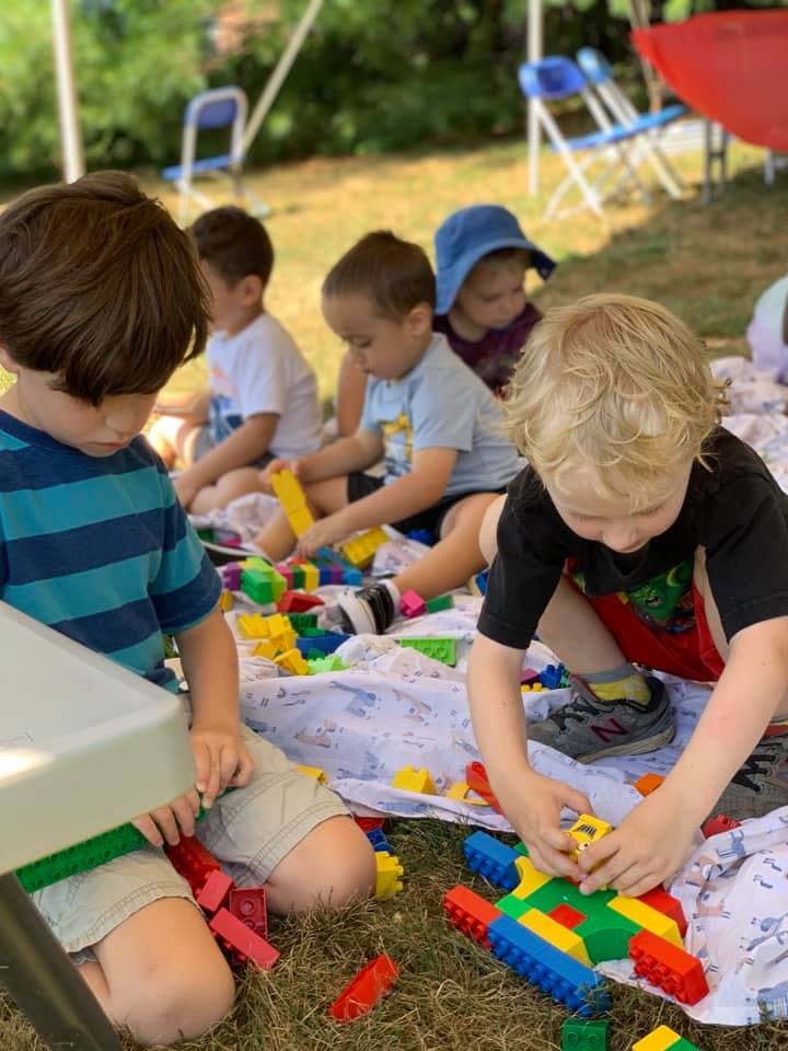 Children playing with colorful building blocks on a blanket outdoors