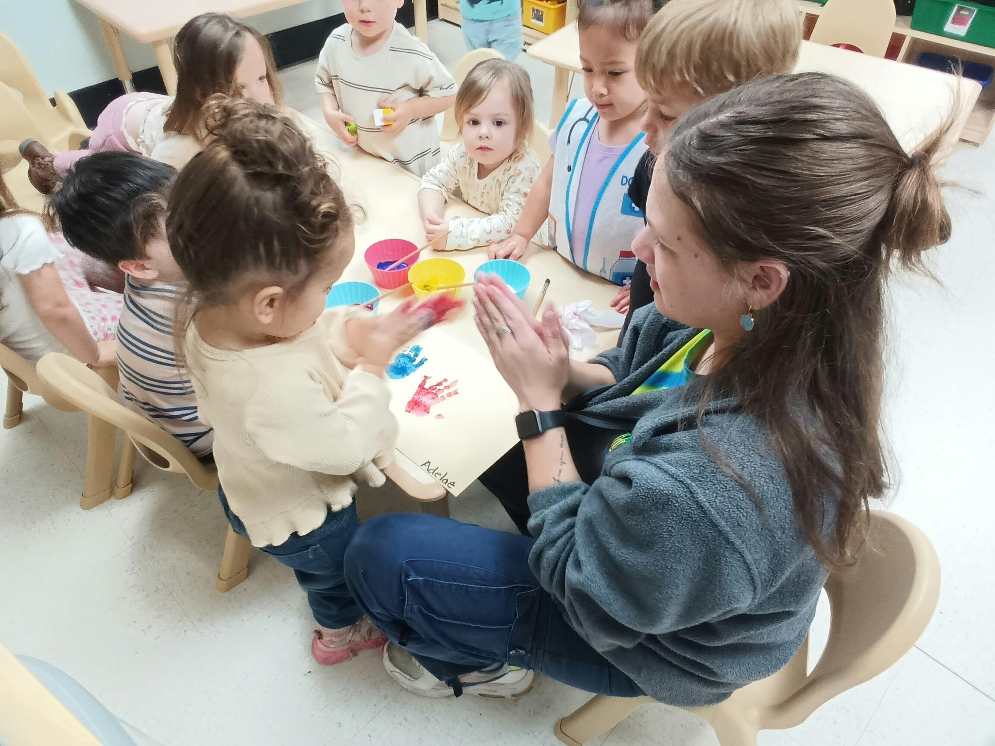 Adult and children gathered around a table with paint and paper