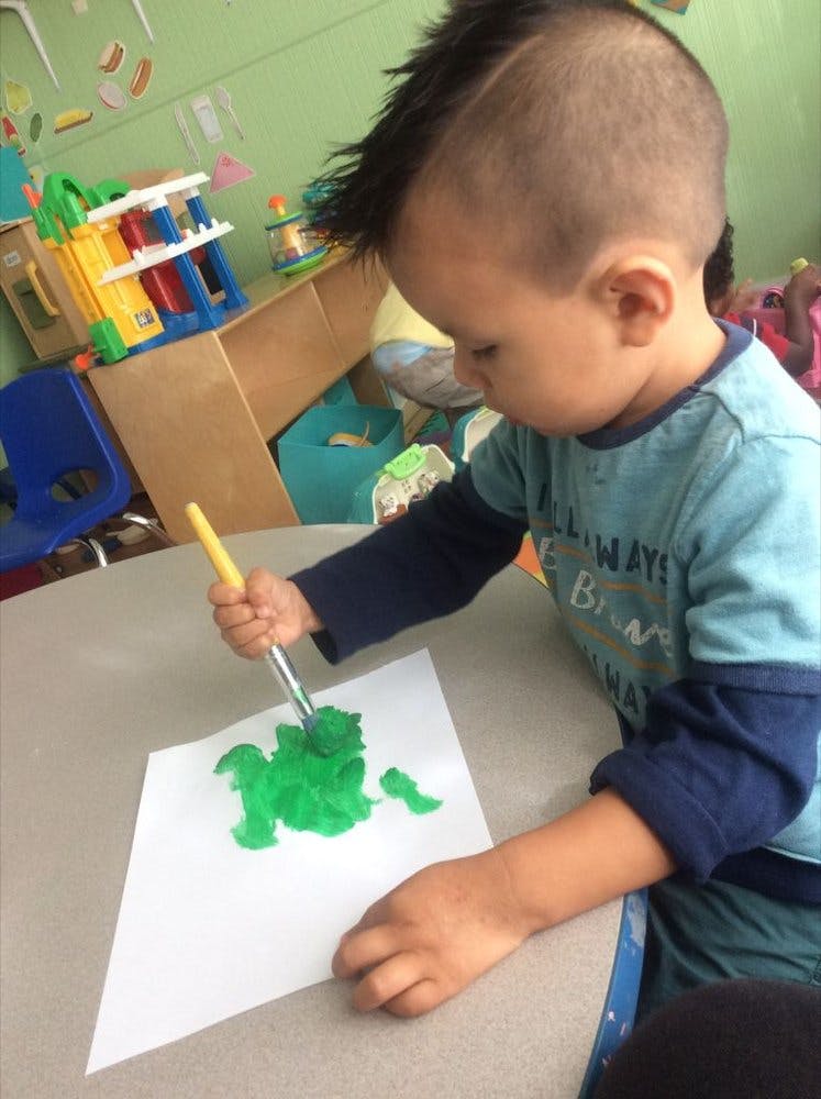 Child painting green on a piece of paper