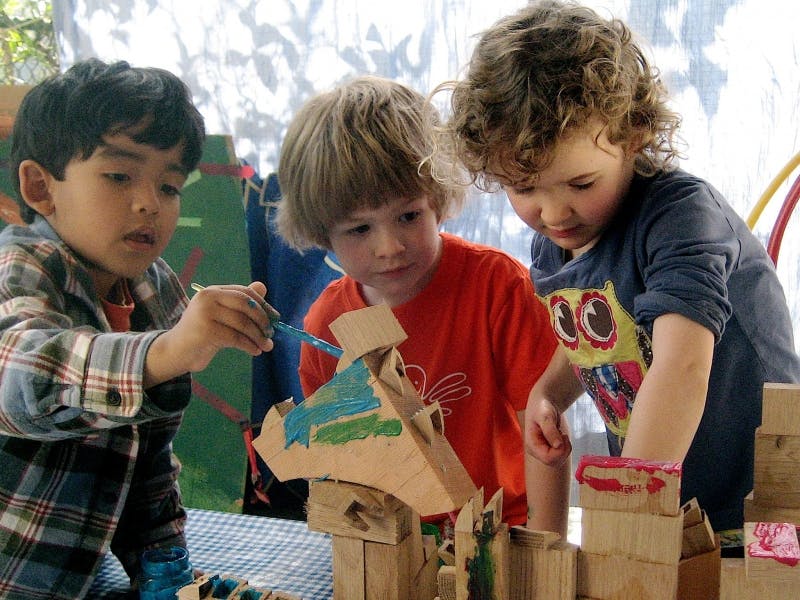 Three children painting cardboard structures
