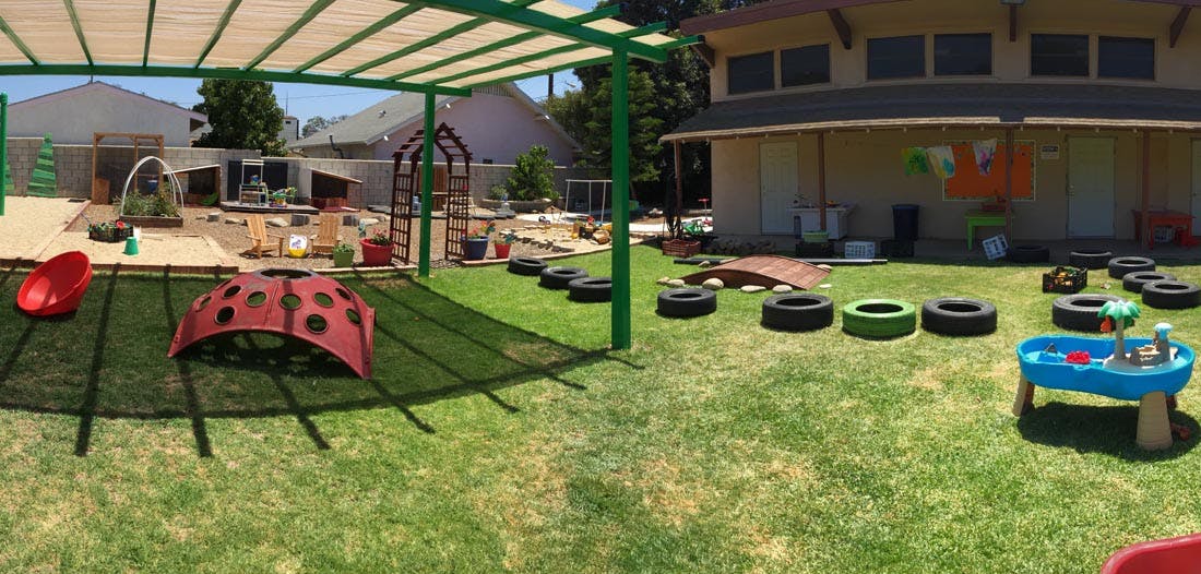 Outdoor play area with shade structure, tires, and play equipment