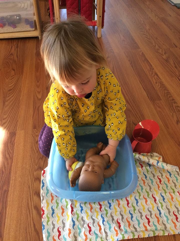 Child playing with a doll in a blue tub