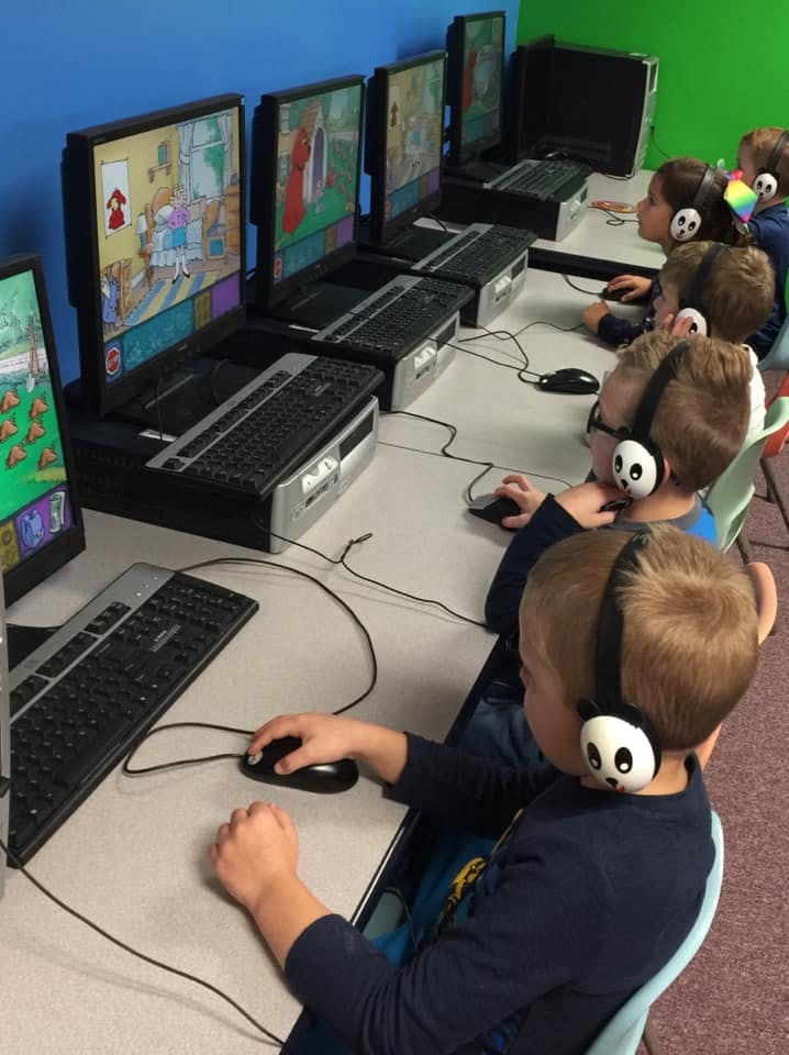Children wearing headphones using computers in a classroom