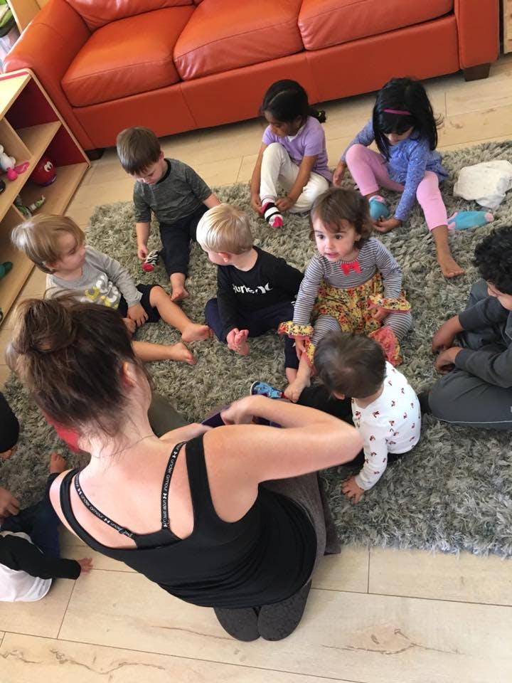 Adult and multiple children sitting on a rug