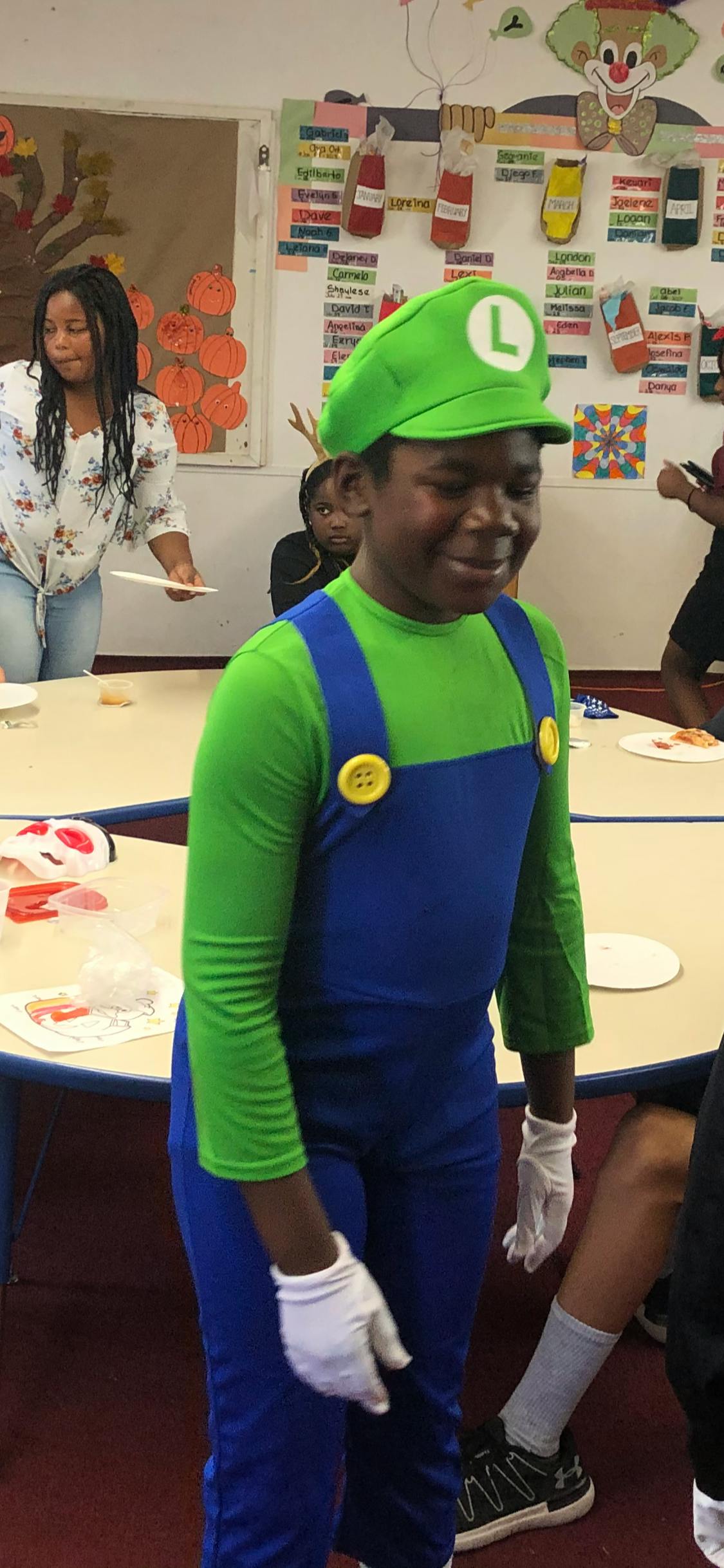 Child in a green shirt and blue overalls with a green hat