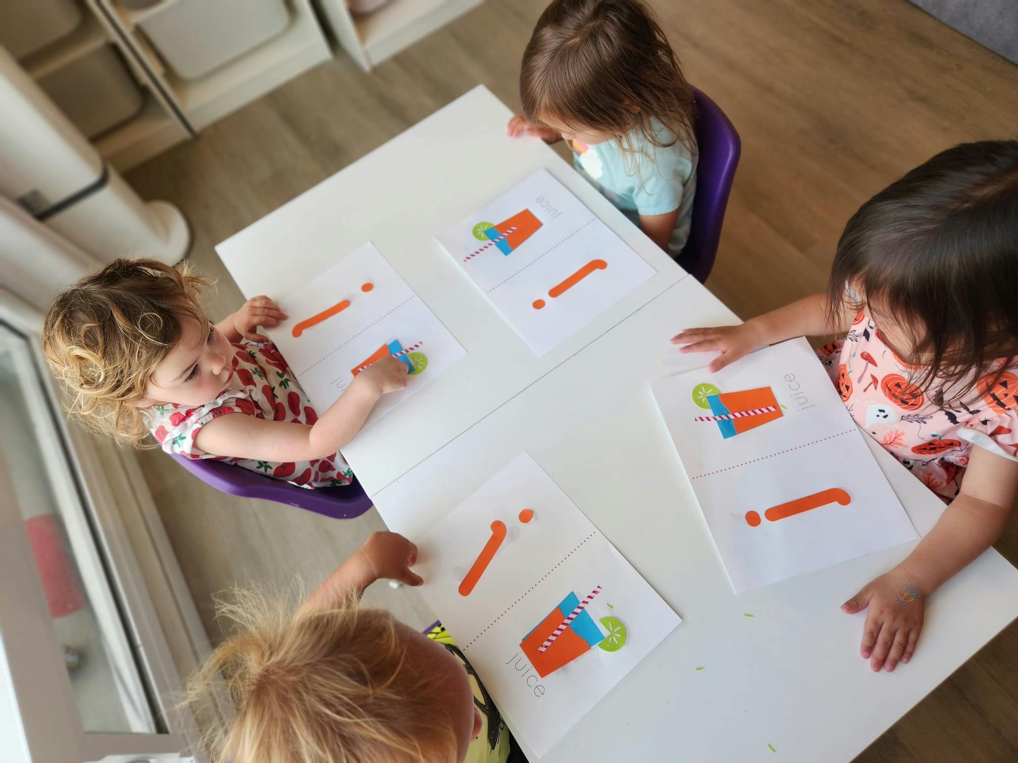 Three children at a table with papers showing popsicles and exclamation points