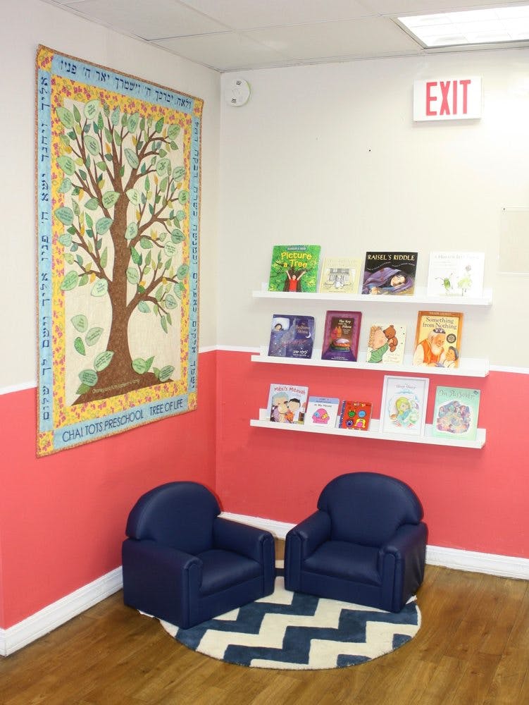 Children's reading nook with two blue chairs, a rug, and bookshelves