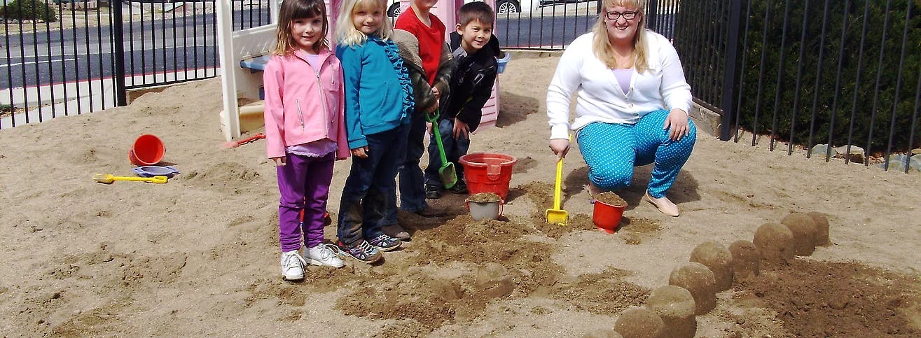Adult and children playing in a sandbox with sand toys