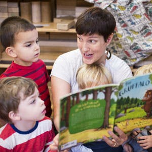 Adult reading a book to three children