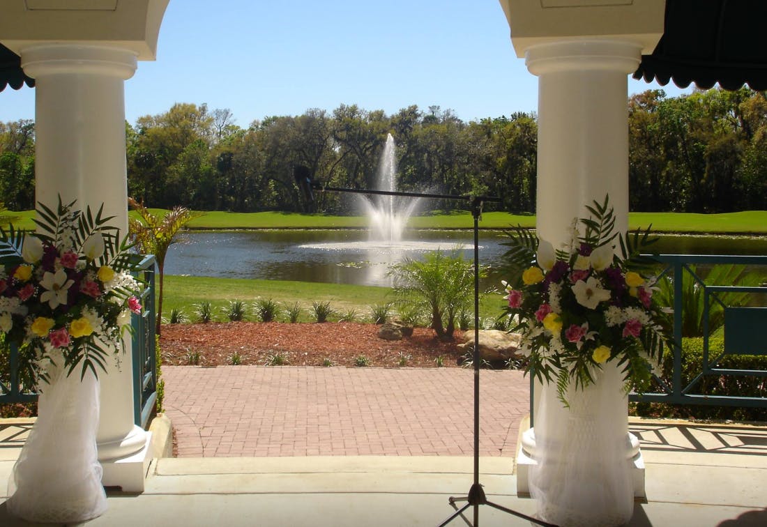 View through columns with floral arrangements to a lake with a fountain
