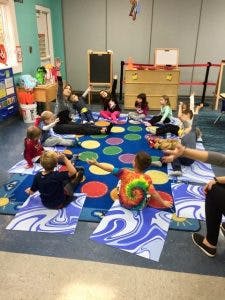Children sitting on a colorful rug in a classroom