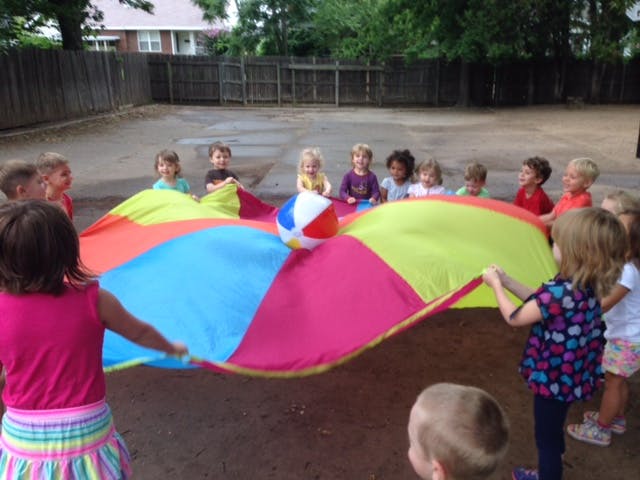 Children playing with a colorful parachute and a beach ball