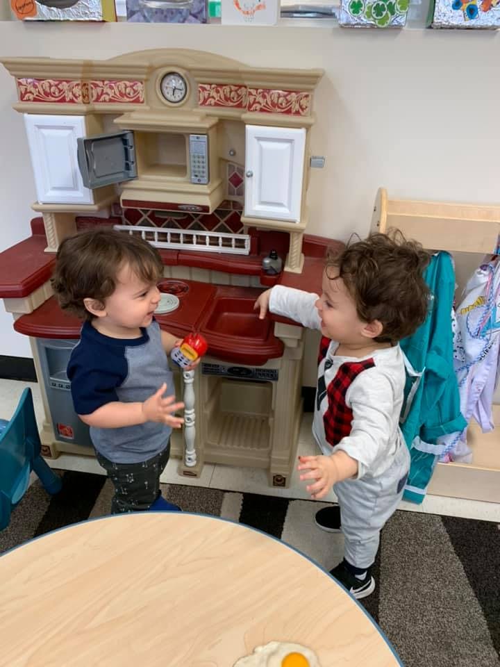 Two children playing with a toy kitchen set