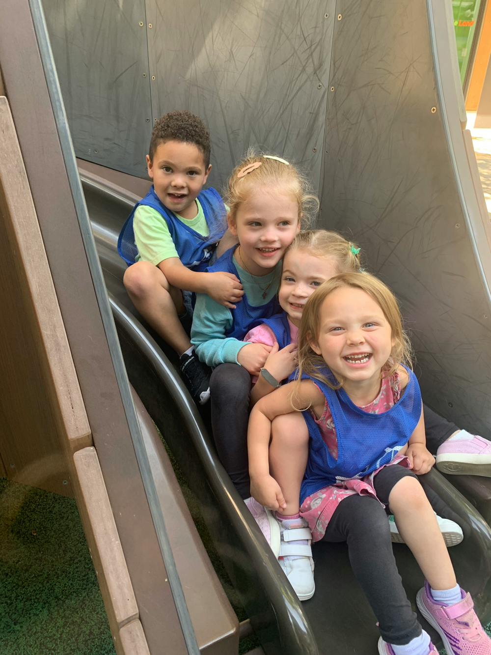 Four children sitting together on a playground slide