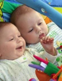Two babies lying on a playmat