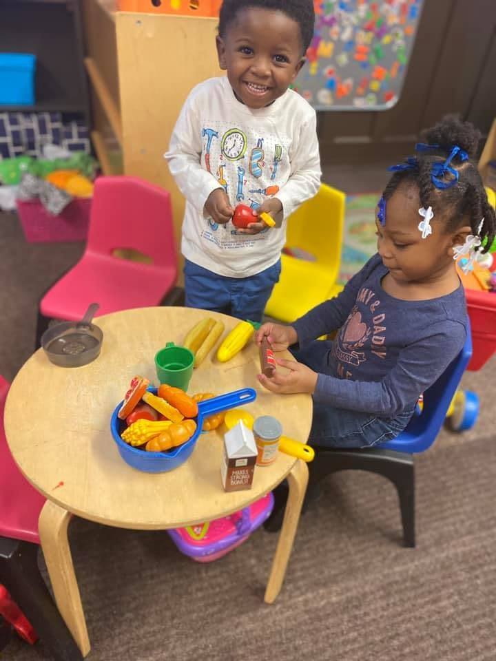 Two children playing with toy food at a small table
