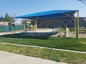 Playground with a blue shade structure over a sandpit