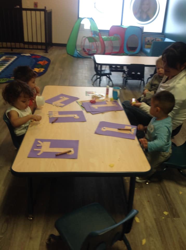 Children and an adult at a table with craft supplies