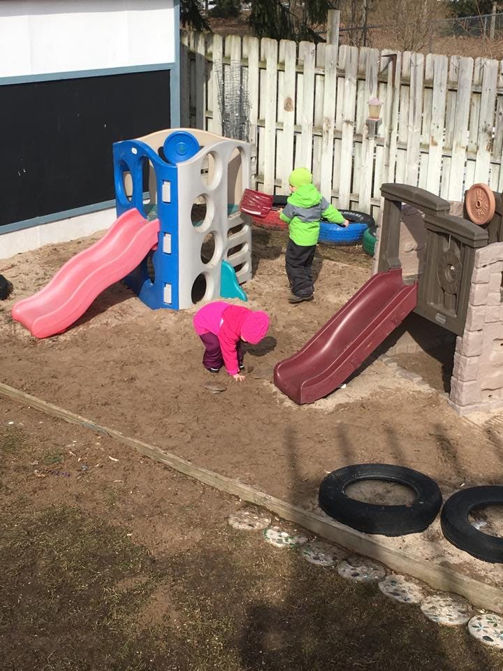 Two children playing in a sandbox with slides and play structures