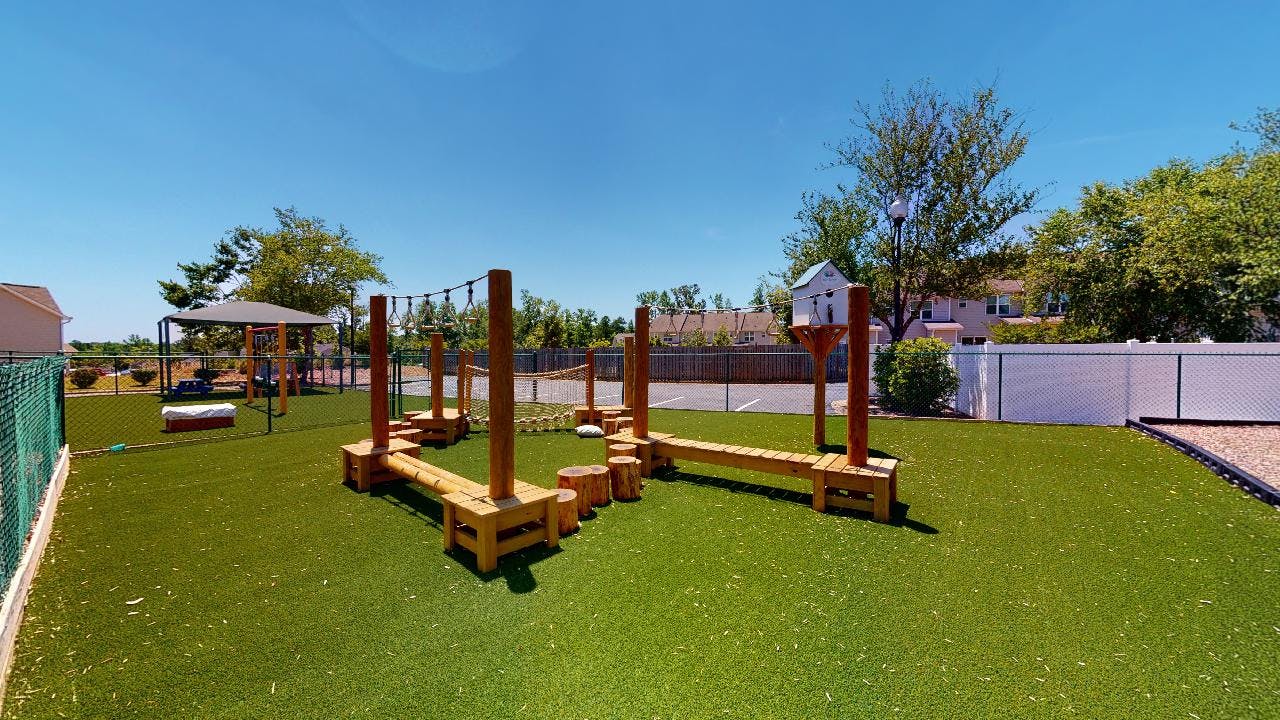 Outdoor playground with wooden balance beams and green turf