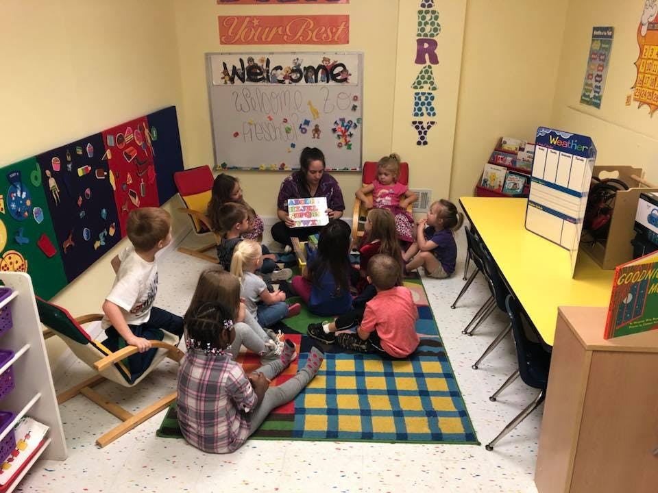 Person reading to a group of children in a classroom