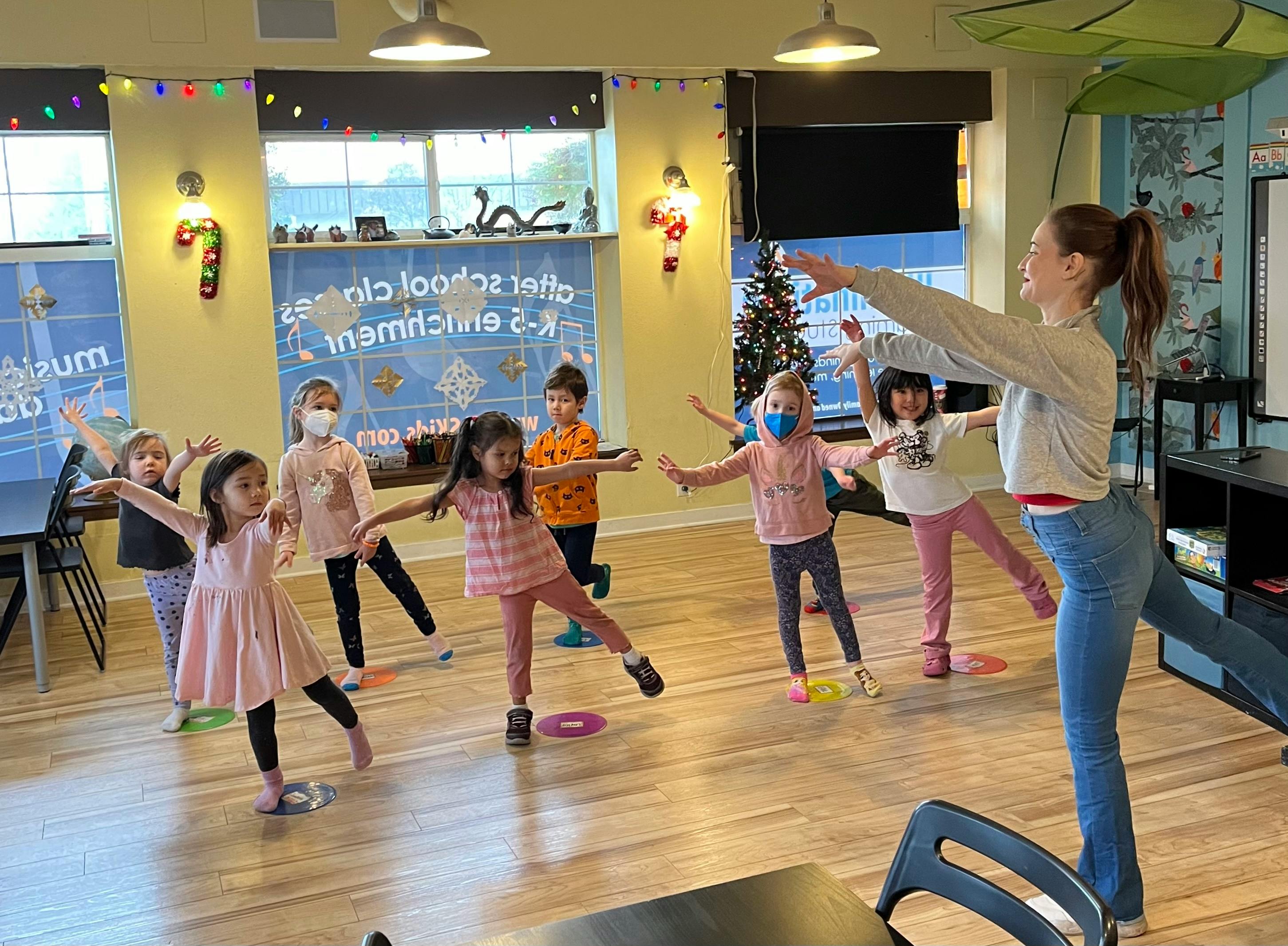 Adult and children in a classroom doing a balancing exercise