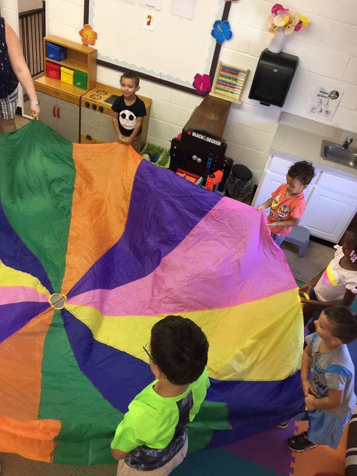Children playing with a colorful parachute in a classroom