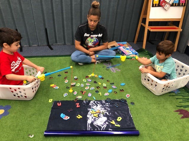 Person and two children playing with fishing rods and magnetic letters