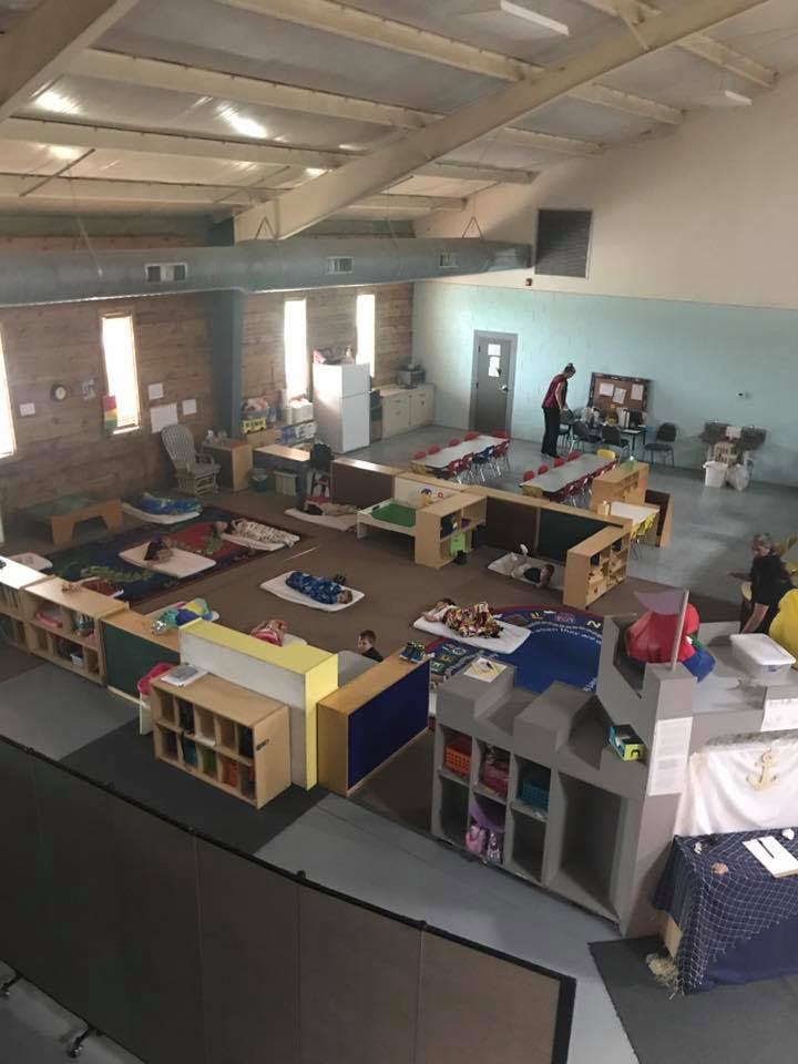 Overhead view of a large room with play areas and a person standing near tables