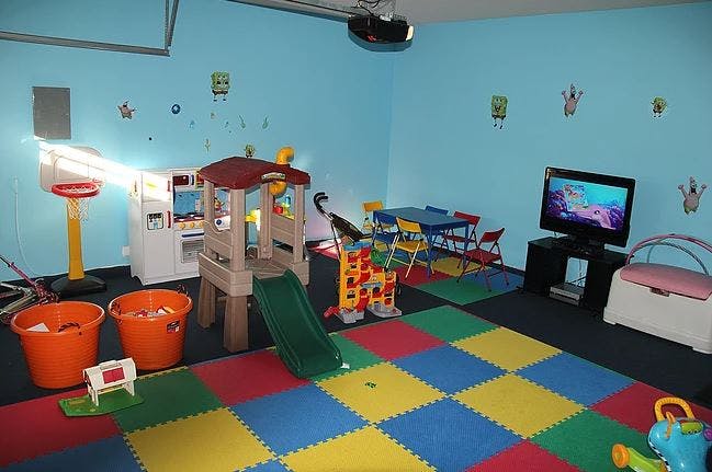 Indoor play area with slide, colorful floor mats, and toys