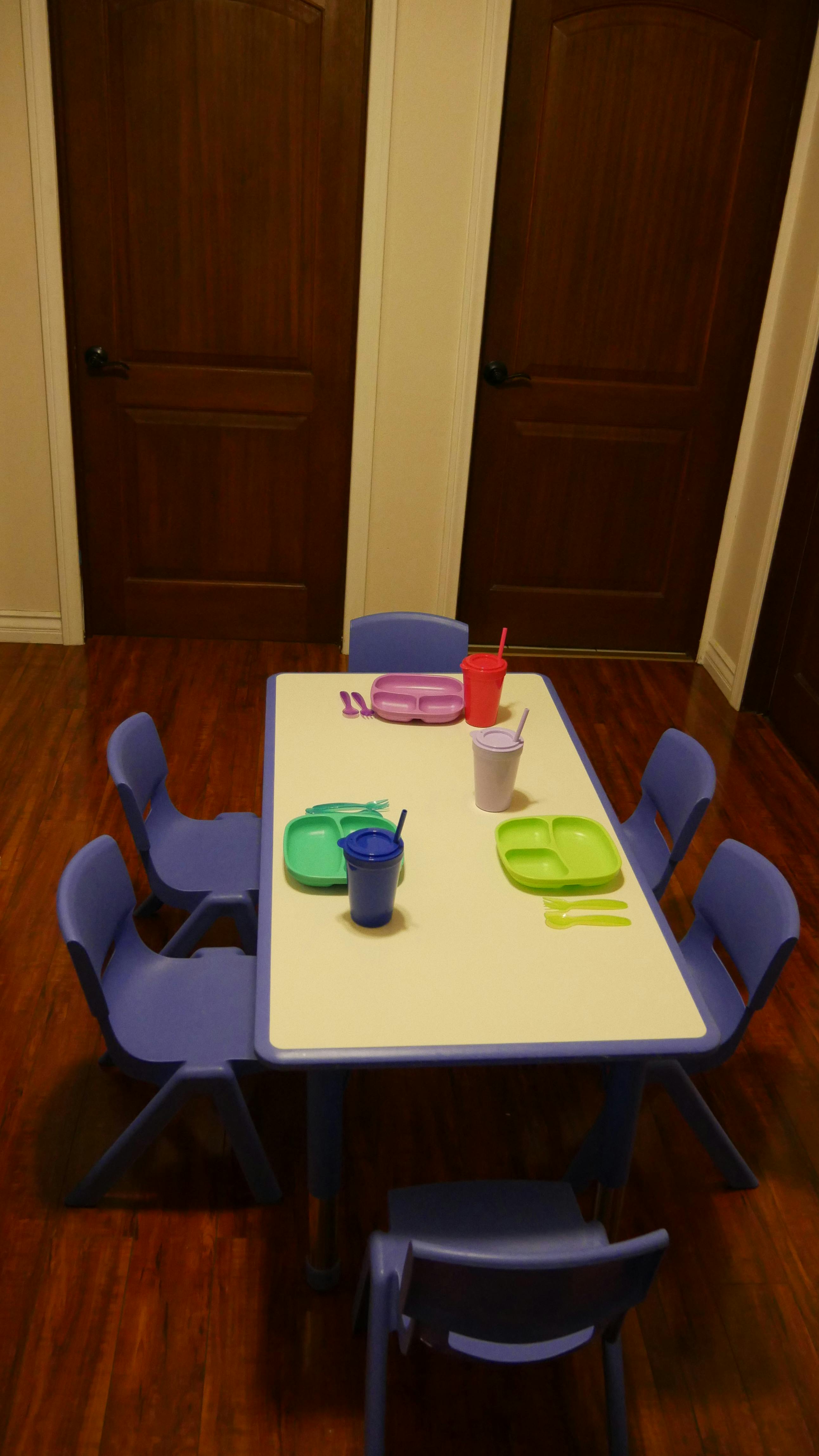 Small table with purple chairs and colorful plates and cups