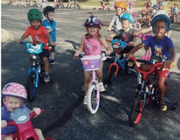 Children on bicycles and tricycles outdoors