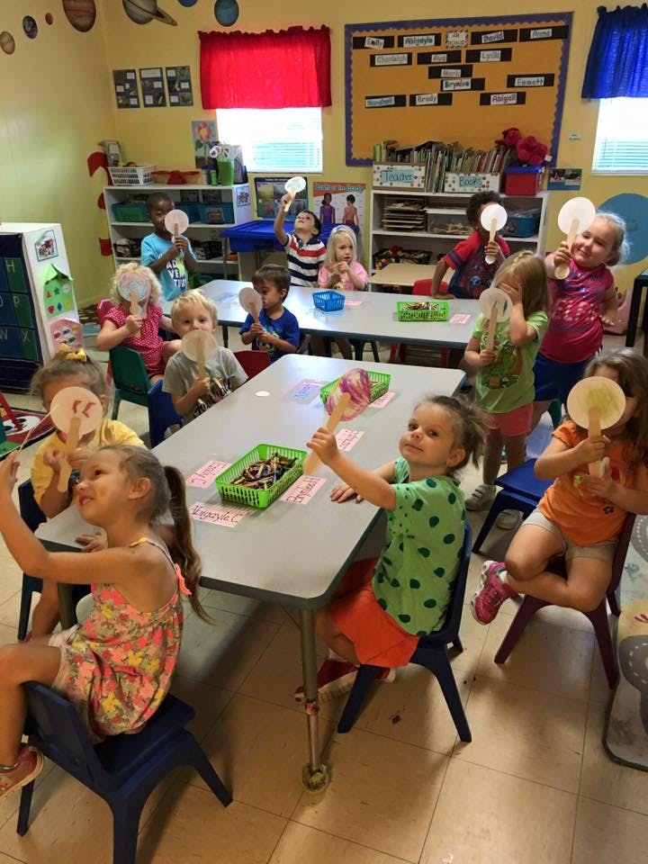 Children in a classroom holding up paper fans