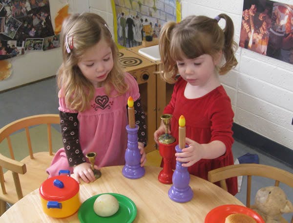 Two children playing with toy candles and dishes at a table