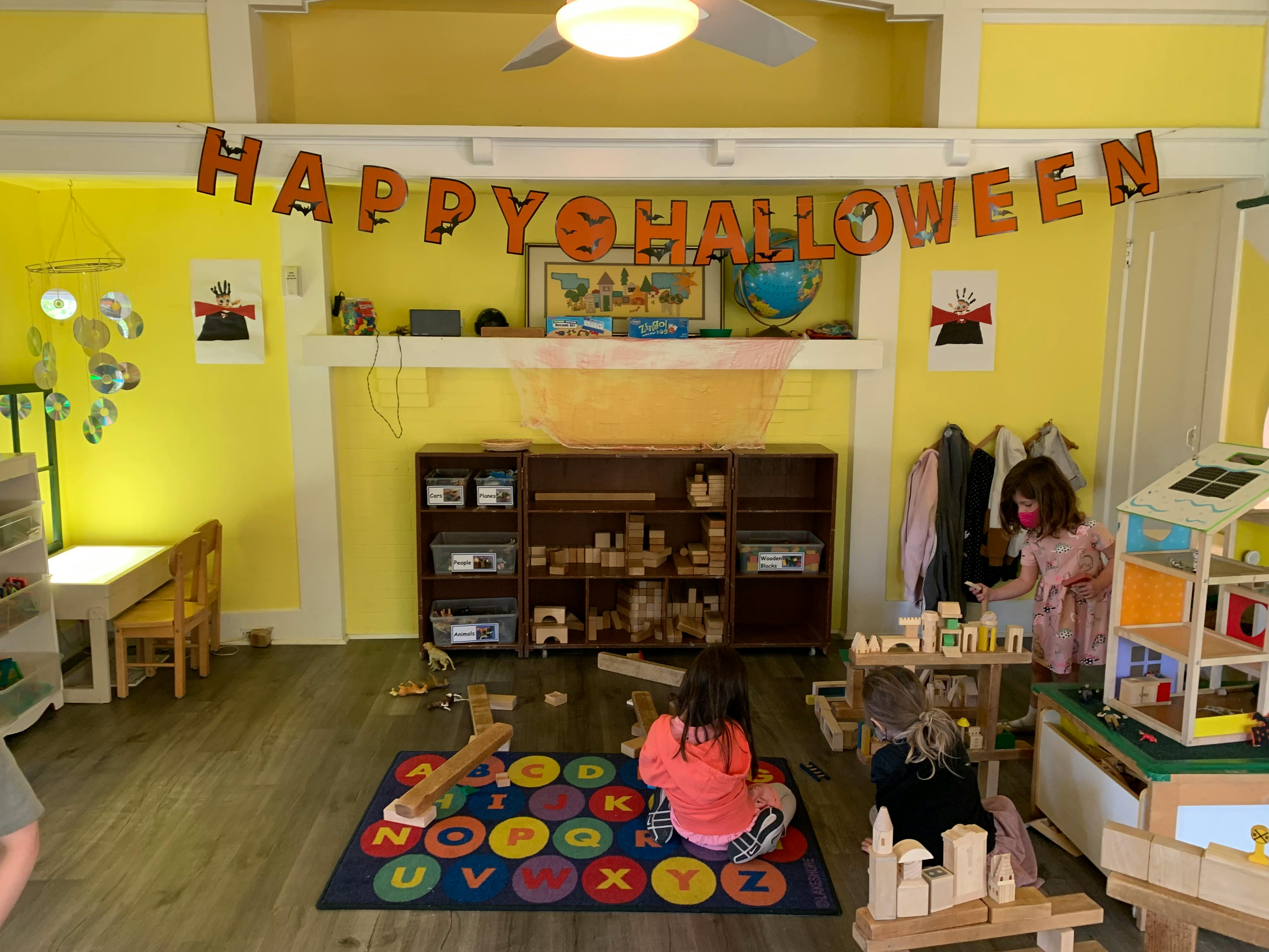 Children playing in a room with a "Happy Halloween" banner
