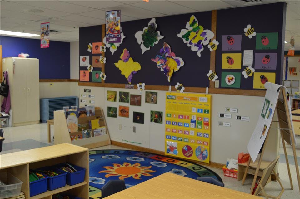 A colorful classroom with a calendar and children's artwork on the wall