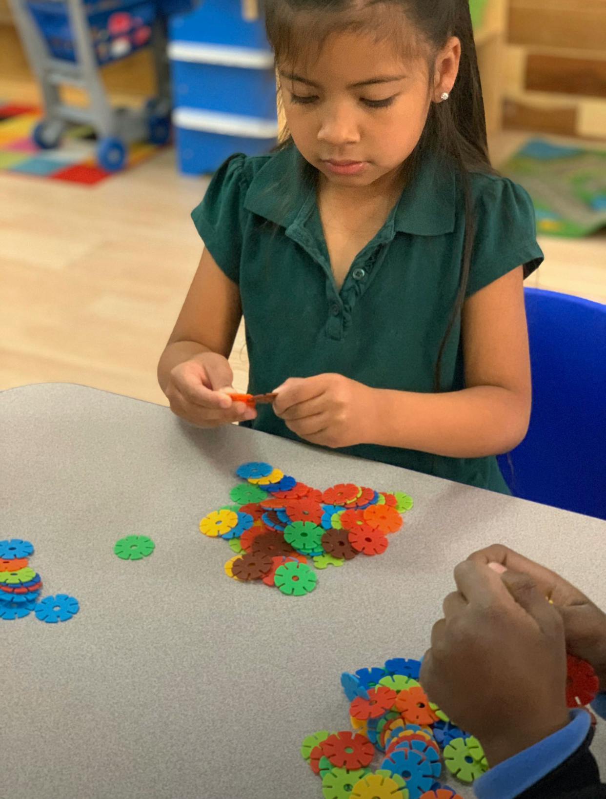 Child playing with colorful interlocking disc toys at a table